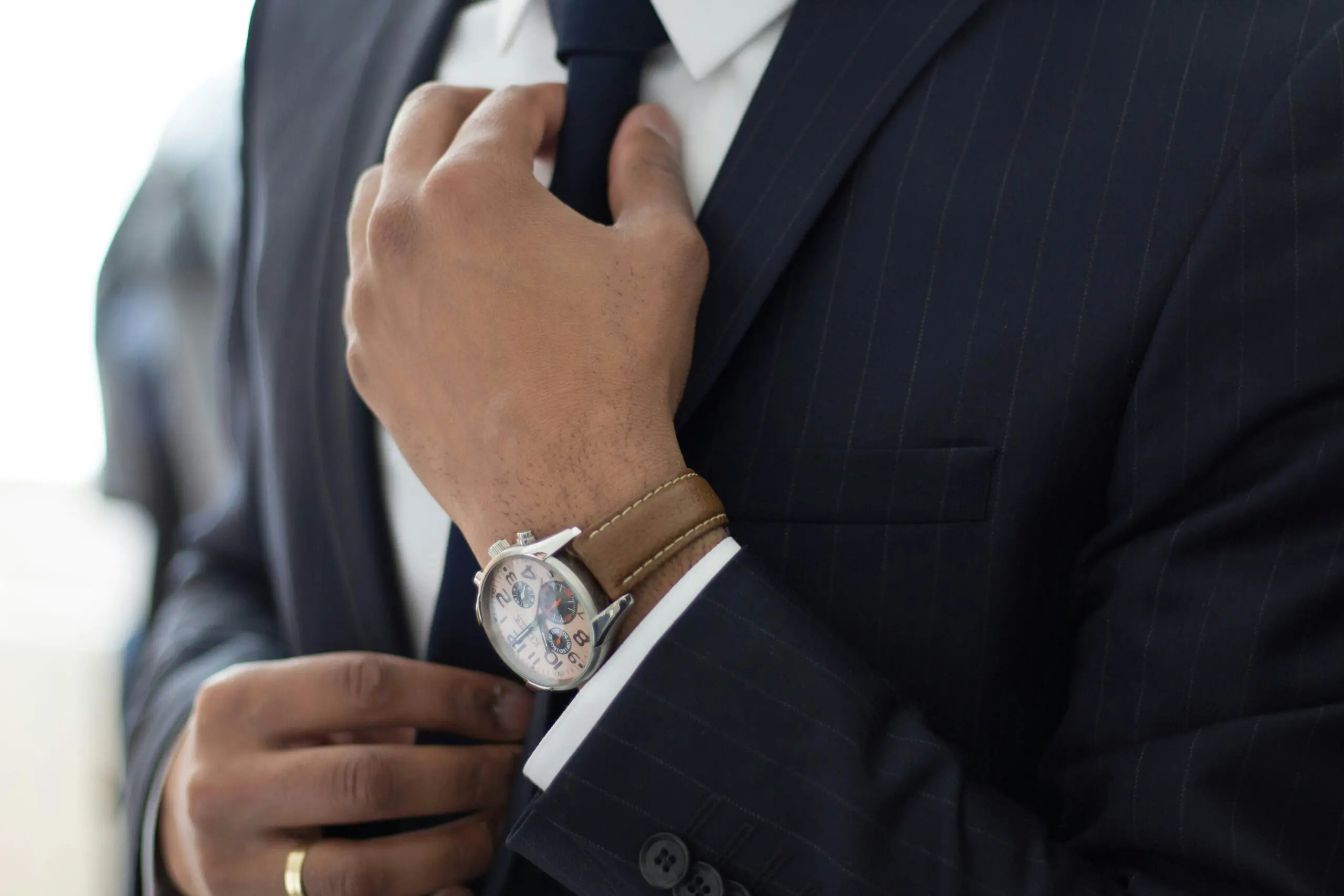 Close-up of a businessman in a pinstripe suit adjusting his tie