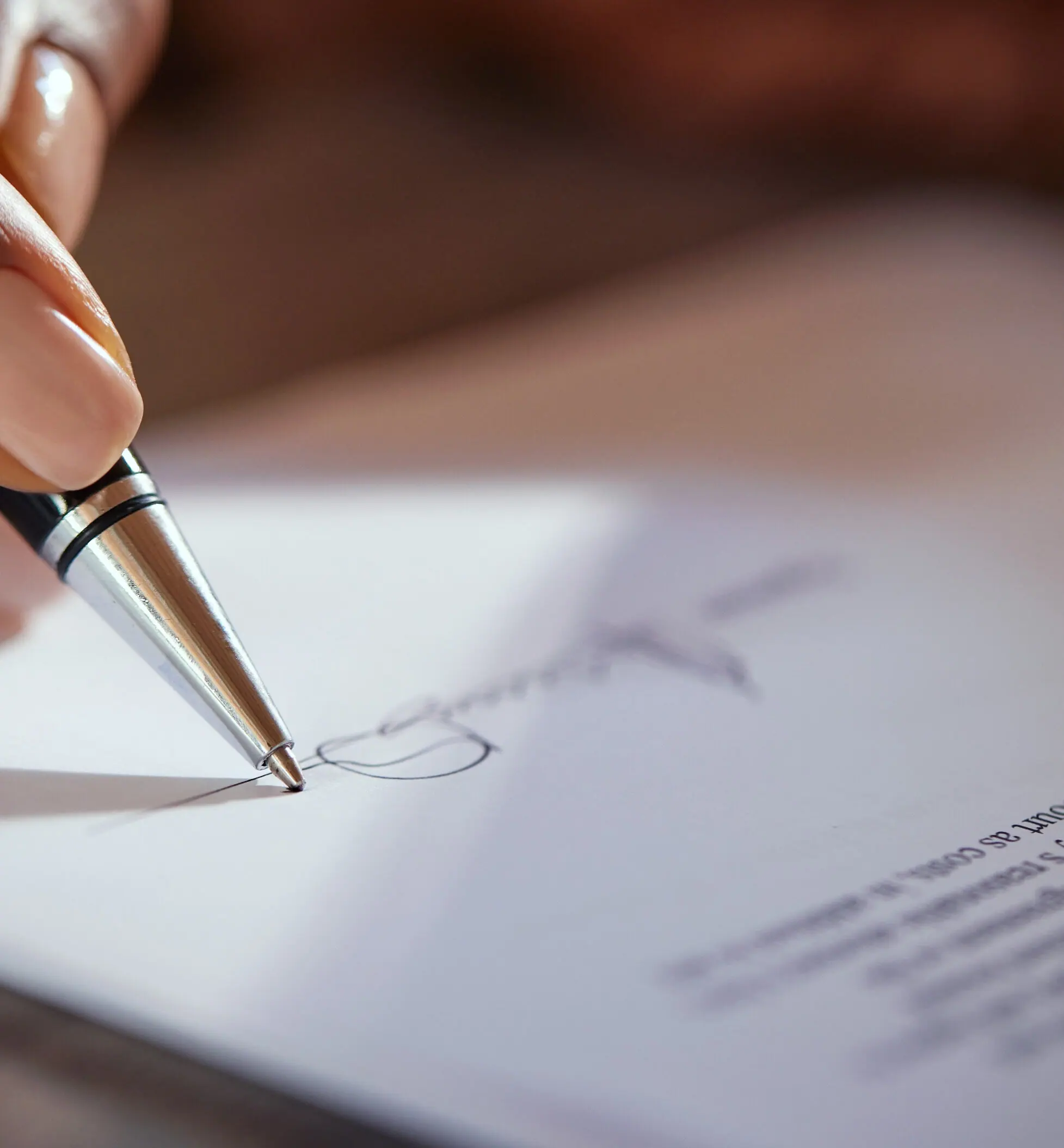 Close-up of a hand signing a document with a pen