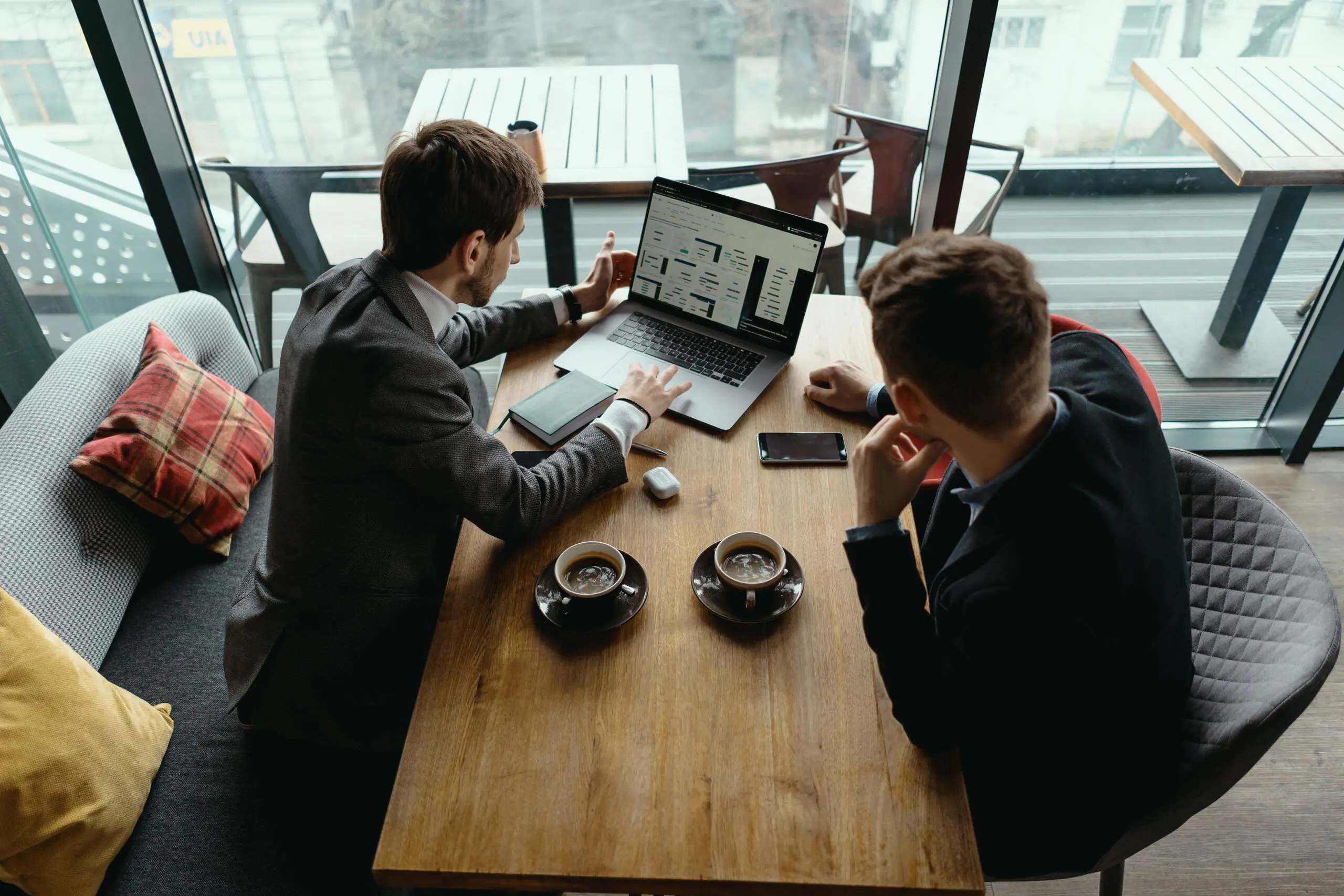 Two colleagues reviewing a bid on a laptop at a café table