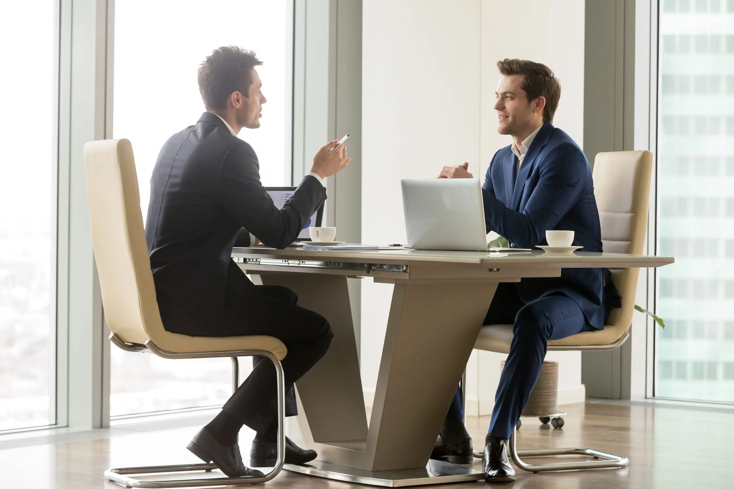 Two businessmen discussing a deal across a conference table