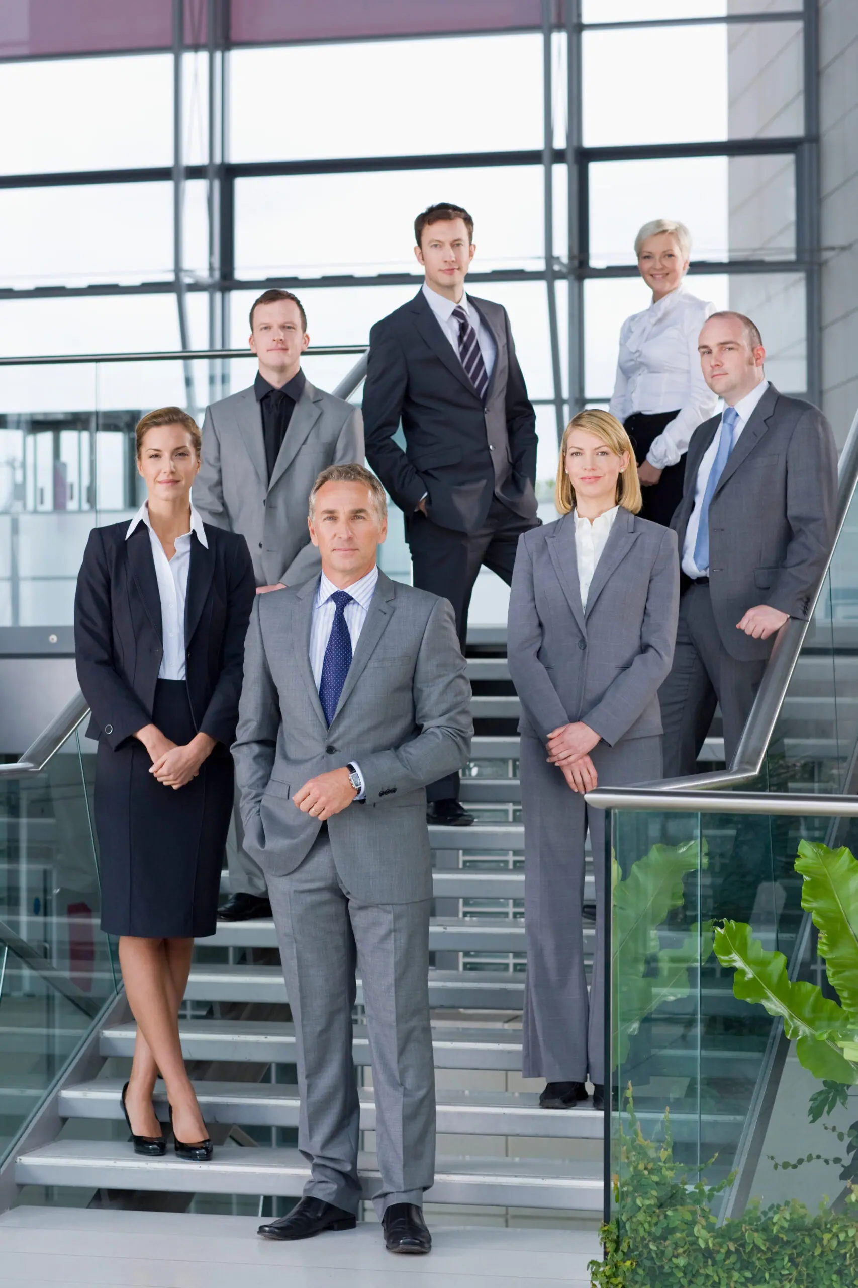 Senior advisory team in business suits standing on an office staircase