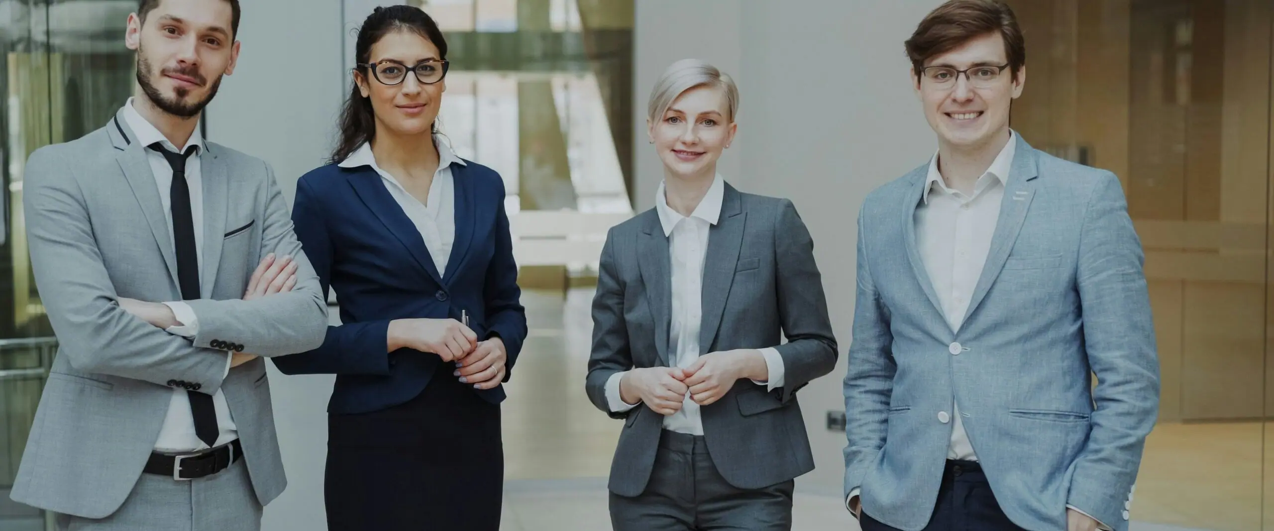 Four smiling business professionals standing together in an office