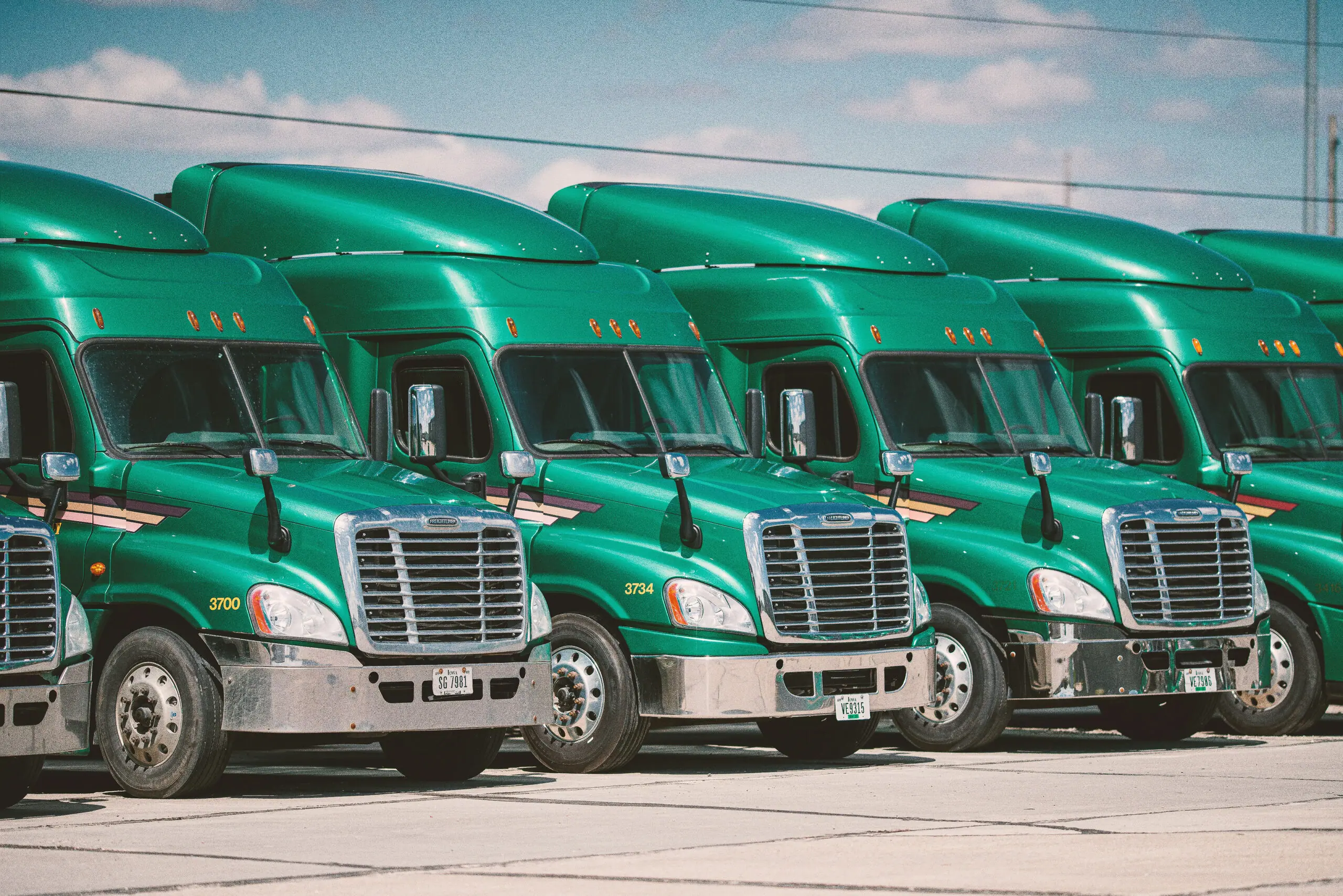 Row of parked green semi-truck tractors